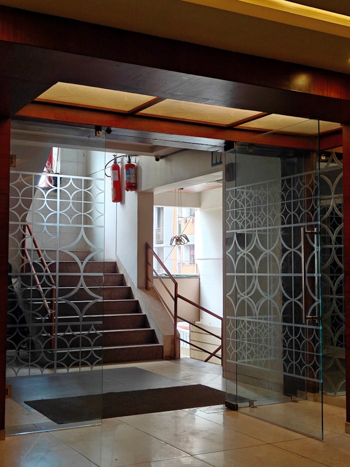 Contemporary glass door entrance of an office building with staircase and fire safety equipment.